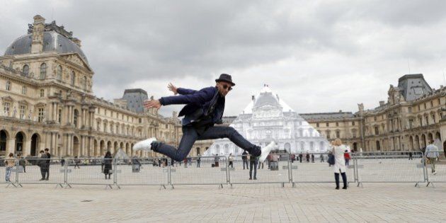 Street artist JR poses in front the Louvre Pyramid in Paris, Tuesday, May 24, 2016. For his latest bold project, street artist JR is creating an eye-tricking installation at the Louvre Museum that makes it seem as if the huge glass pyramid at the heart of the courtyard has disappeared. (AP Photo/Francois Mori)