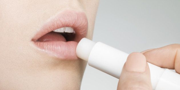 Female applying lip balm, close up, side view