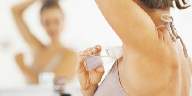 Closeup on woman applying roller deodorant on underarm