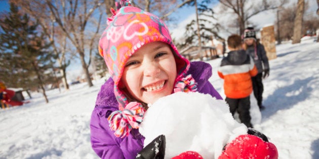 Caucasian girl holding snowball outdoors