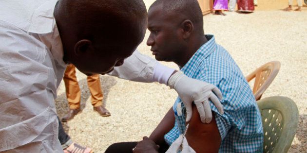 A health worker, left, injects a man in his arm with an Ebola vaccine in Conakry, Guinea, March 7, 2015. The World Health Organization will start large-scale testing of an experimental Ebola vaccine in Guinea on Saturday to see how effective it might be in preventing future outbreaks of the deadly virus. The West African nations of Sierra Leone, Liberia and Guinea have been hardest hit in the yearlong Ebola outbreak, which is estimated to have left more than 9,800 people dead. (AP Photo/ Youssouf Bah)
