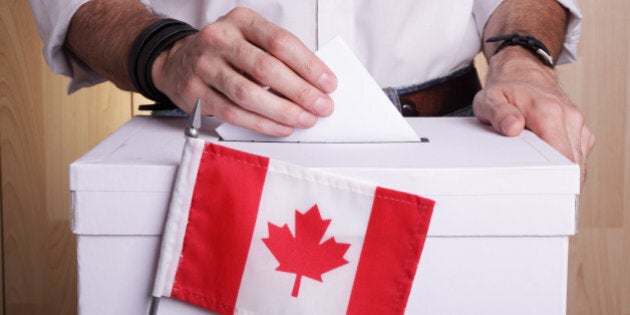 A man casting his vote. The Canadian flag is in front of the ballot box