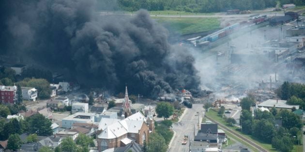 Smoke rises from railway cars that were carrying crude oil after derailing in downtown Lac Megantic, Quebec, Canada, Saturday, July 6, 2013. A large swath of Lac Megantic was destroyed Saturday after a train carrying crude oil derailed, sparking several explosions and forcing the evacuation of up to 1,000 people. (AP Photo/The Canadian Press, Paul Chiasson)