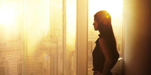 Business woman looking over the city at sunrise.