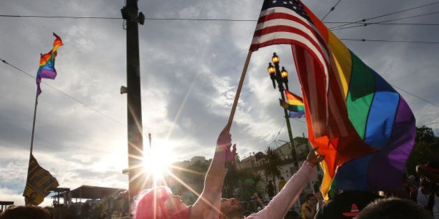 SAN FRANCISCO, CA - JUNE 27: A woman helps Francisco Pavon, center, wave a rainbow pride flag and an American flag during a gay pride celebration on June 27, 2015 in San Francisco, California. The Supreme Court ruled that same-sex couples have a constitutional right to marry nationwide without regard to their state's laws. (Photo by Elijah Nouvelage/Getty Images)