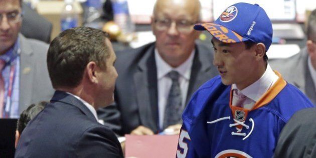 Andong Song, of China, shakes hands with a team executive after being chosen 172nd overall by the New York Islanders during the sixth round of the NHL hockey draft, Saturday, June 27, 2015, in Sunrise, Fla. (AP Photo/Alan Diaz)