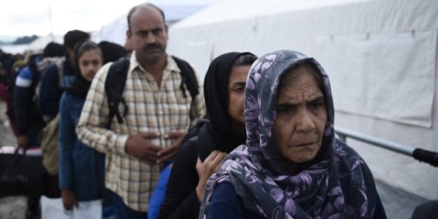 An elderly Afghan woman, right, waits in a queue to be allowed to cross from the northern Greek village of Idomeni to southern Macedonia, Friday, Oct. 9, 2015. Very few of those arriving in Greece want to stay in the financially stricken country, instead moving north through the Balkans to more prosperous European Union countries such as Germany, Austria and Sweden.(AP Photo/Giannis Papanikos)