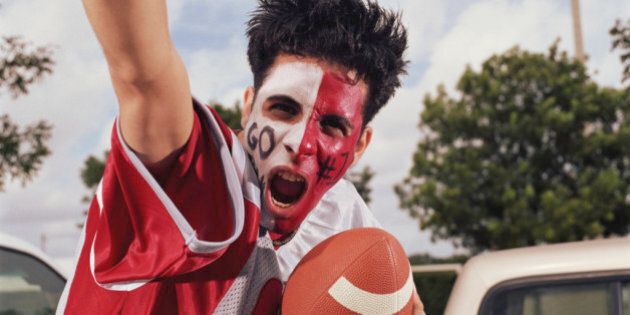 Young man with painted face, cheering and holding football