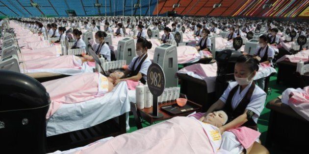 Beauticians apply facial care to women as they lay on beds in a stadium in Jinan, east China's Shandong province on May 4, 2015. A total of 1000 beauticians applied facial care to 1000 women at the same time in the open air to break a Guinness World Record, local media reported. CHINA OUT AFP PHOTO (Photo credit should read STR/AFP/Getty Images)
