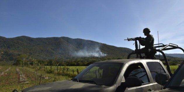 A soldier of the 88 infantry brigade observes as smoke raises after a military helicopter was shot down in Villa Vieja community, Villa Purificacion, Jalisco State, Mexico on May 2, 2015. Mexican authorities searched Saturday for three missing soldiers after gunmen brought down their helicopter in a field during an antinarcotics cartel operation that sparked mayhem in Jalisco state. AFP PHOTO / Yuri COREZ (Photo credit should read YURI CORTEZ/AFP/Getty Images)
