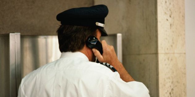 Security guard using telephone, rear view