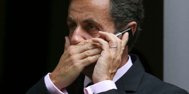 French President Nicolas Sarkozy covers his mouth while speaking on the phone outside the French Consulate in New York, Friday, July 17, 2009(AP Photo/Mary Altaffer)