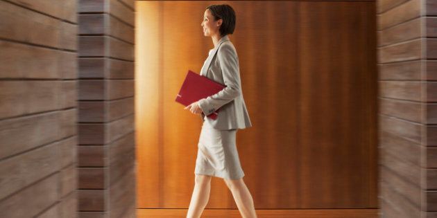 Businesswoman with folder walking in office corridor