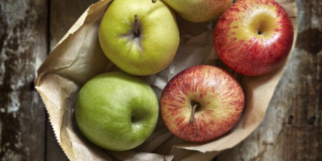 Assorted apples and pears on brown paper and a wooden work surface.