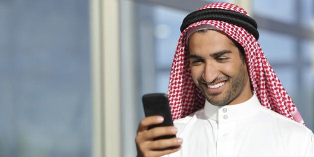 Arab saudi businessman working with his phone with an office building in the background