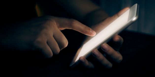 Hand touching digital tablet in darkroom