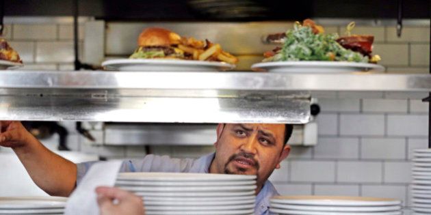 In this photo taken Tuesday, March 31, 2015, cook Alex Romero looks out from the kitchen at the Skillet Diner in Seattle. Seattleâs new minimum wage law went into effect Wednesday, April 1, 2015, that will eventually raise the city's minimum wage to $15 an hour. Starting Wednesday, large businesses and national chains must raise their minimum pay to at least $11 an hour. Smaller businesses must pay at least $10 an hour. Seattle's current minimum wage is $9.47, the same as the Washington state minimum wage. (AP Photo/Elaine Thompson)