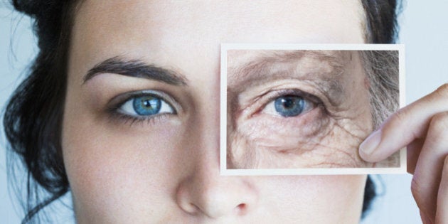 Young woman with photo of aged eye over her own