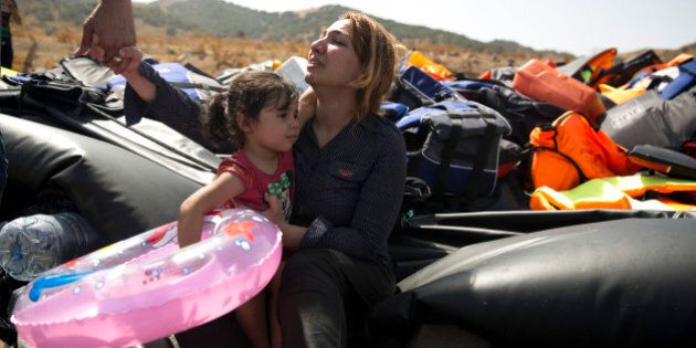 A Syrian family react after arrived with others aboard a dinghy from Turkey, on the island of Lesbos, Greece, Monday, Sept. 7, 2015. The island of some 100,000 residents has been transformed by the sudden new population of some 20,000 refugees and migrants, mostly from Syria, Iraq and Afghanistan. (AP Photo/Petros Giannakouris)
