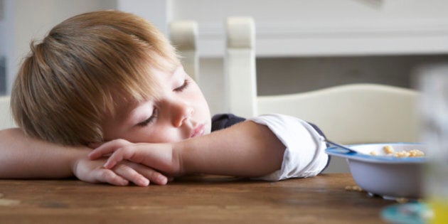 boy asleep on the kitchen table at breakfast time