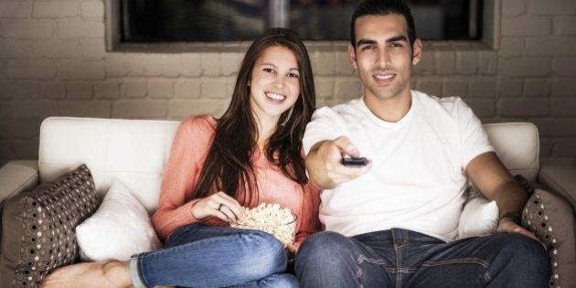 A young couple watching TV at night. Special attention was placed on creating realistic lighting.Our images are processed from