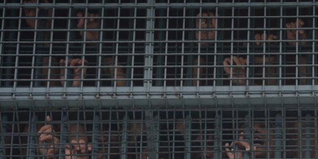 Inmates peer out from a metal grill window at the city jail hours after an attempted jail break by other prisoners in Paranaque, suburban Manila on August 12, 2016.Ten prisoners in the Philippines were killed when a suspected jailbreak and attempt to kidnap the warden went wrong in a Manila suburb, authorities said on August 12. / AFP / TED ALJIBE (Photo credit should read TED ALJIBE/AFP/Getty Images)