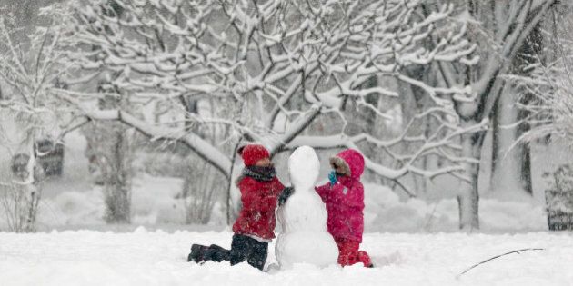 Children build a snowman in a park in Bucharest, Romania, Monday, Dec. 29, 2014. Romania, especially the eastern part, is affected by heavy snow falls and blizzards this year that cause traffic disruptions but are enjoyed by children and mountain tourists. (AP Photo/Vadim Ghirda)