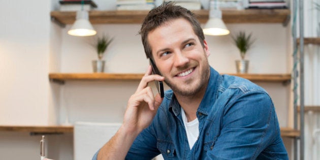 Portrait of young businessman talking on mobile phone in office