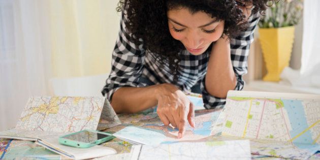 Mixed race woman planning road trip with maps