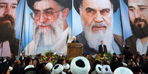 Iranian President Hassan Rouhani delivers a speech under portraits of Iran's supreme leader, Ayatollah Ali Khamenei (Center L) and Iran's founder of the Islamic Republic, Ayatollah Ruhollah Khomeini (Center R), on the eve of the 25th anniversary of the Islamic revolutionary leader Ayatollah Ruhollah Khomeini's death, at his mausoleum in a suburb of Tehran on June 3, 2014. AFP PHOTO / ATTA KENARE (Photo credit should read ATTA KENARE/AFP/Getty Images)