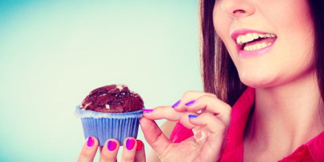 Sweet food sugar make us happy. Smiling woman holds cake chocolate muffin in hand blue background