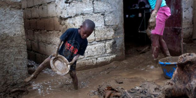 Winsky Pierre, left, 5, helps to drain mud from his flooded house after the passing of Tropical Storm Isaac in Port-au-Prince, Haiti, Sunday Aug. 26, 2012. The death toll in Haiti from Tropical Storm Isaac has climbed to seven after an initial report of four deaths, the Haitian government said Sunday. (AP Photo/Dieu Nalio Chery)
