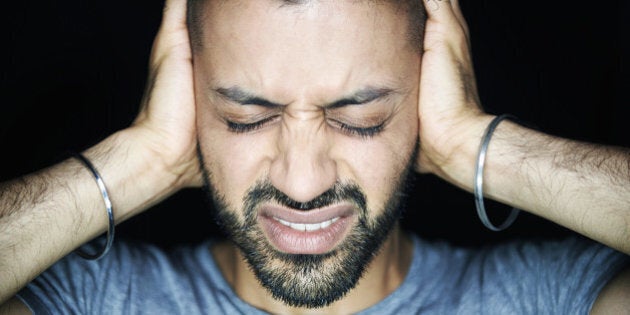 man blocking ears looking stressed