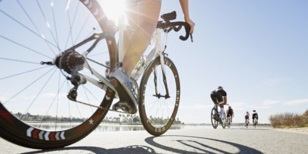 Rear view of triathletes cycling on street