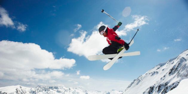 Male skier performing jump off Bansko mountain cornice