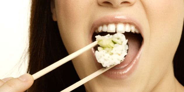 Woman eating sushi with chopsticks, close up of mouth