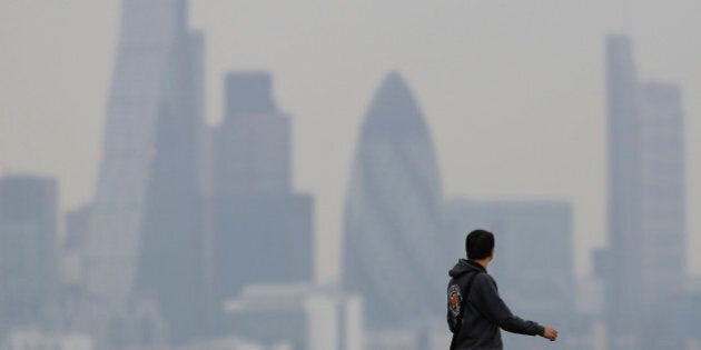 A man walks through Greenwich Park as a haze of pollution sits over the London skyline April 3, 2014. REUTERS/Luke MacGregor