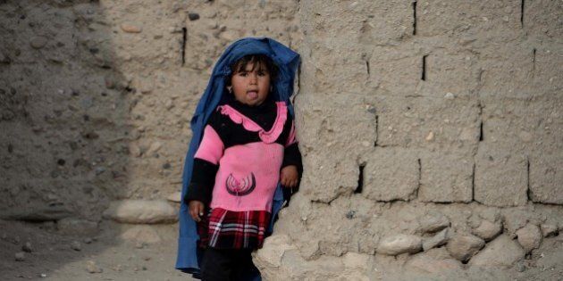 In this photograph taken on February 6, 2015, a young Afghan girl wears a burqa cut to her size as she stands in the doorway of her home on the outskirts of Jalalabad. AFP PHOTO / Noorullah Shirzada (Photo credit should read Noorullah Shirzada/AFP/Getty Images)