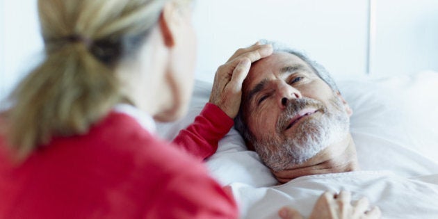 Rear view of woman caressing ill man in hospital ward