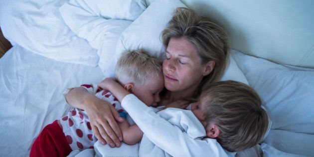 Mother with sons sleeping in bed