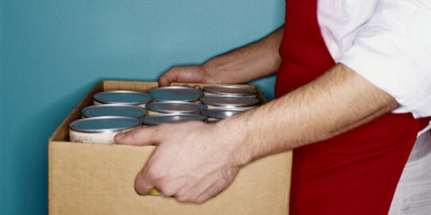 Clerk carrying box of canned goods, mid section, side view