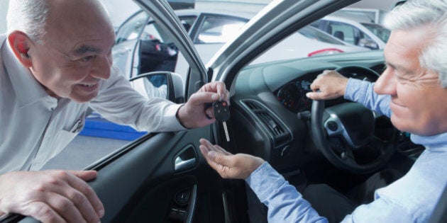 Hispanic car salesman handing keys to customer
