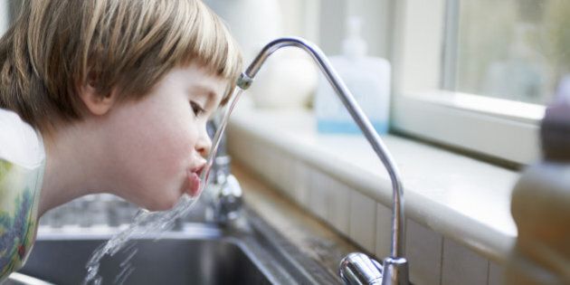 young boy drinking water from tap