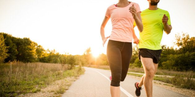 Detail of young people jogging together in nature with sun setting behind them.