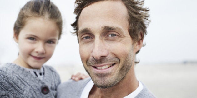 Father carrying daughter on the beach, portrait