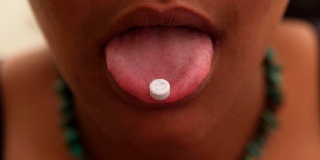 Girl with an ecstasy tablet on her tongue, smiley faced pill, UK 2004