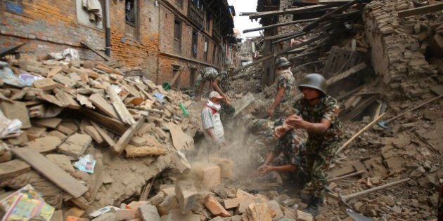 Rescue workers remove debris as they search for victims of earthquake in Bhaktapur near Kathmandu, Nepal, Sunday, April 26, 2015. A strong magnitude 7.8 earthquake shook Nepal's capital and the densely populated Kathmandu Valley before noon Saturday, causing extensive damage with toppled walls and collapsed buildings, officials said. (AP Photo/Niranjan Shrestha)