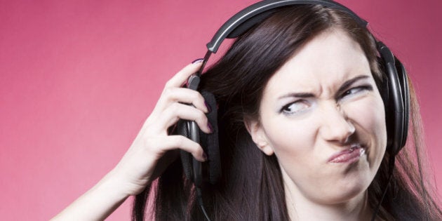 young beautiful girl with professional headphones on a pink background