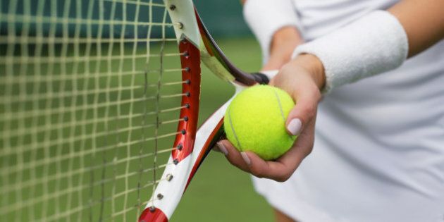 Close-up of tennis player holding racket and ball in hands