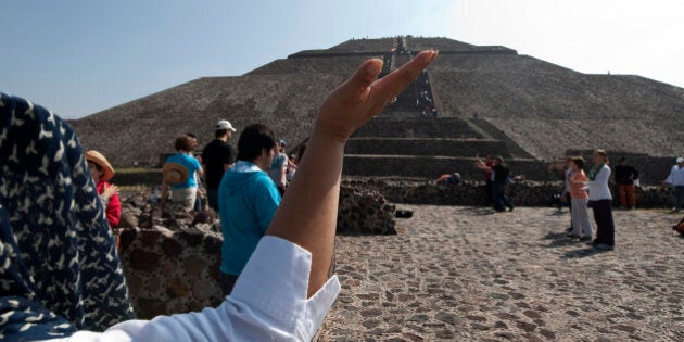 A tourist raises her hands to the sun to take its energy in front of the Pyramid of Sun in Teotihuacan archaeological site, Mexico State, Mexico on November 11, 2011. People gathered around the pyramids in Teotihuacan seeking for harmony on the date 11/11/11. AFP PHOTO/OMAR TORRES (Photo credit should read OMAR TORRES/AFP/Getty Images)